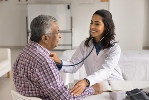 Female doctor checking vitals on an older gentleman.