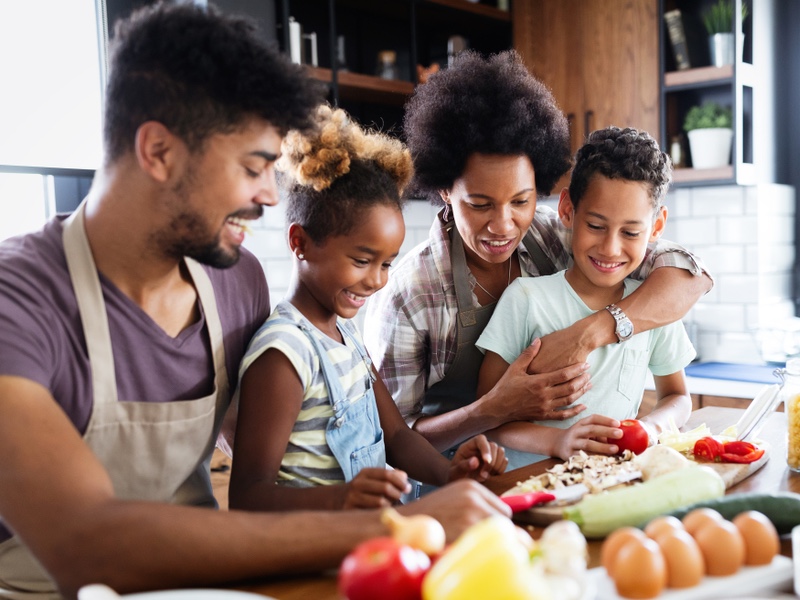 A family preparing dinner around a kitchen counter.