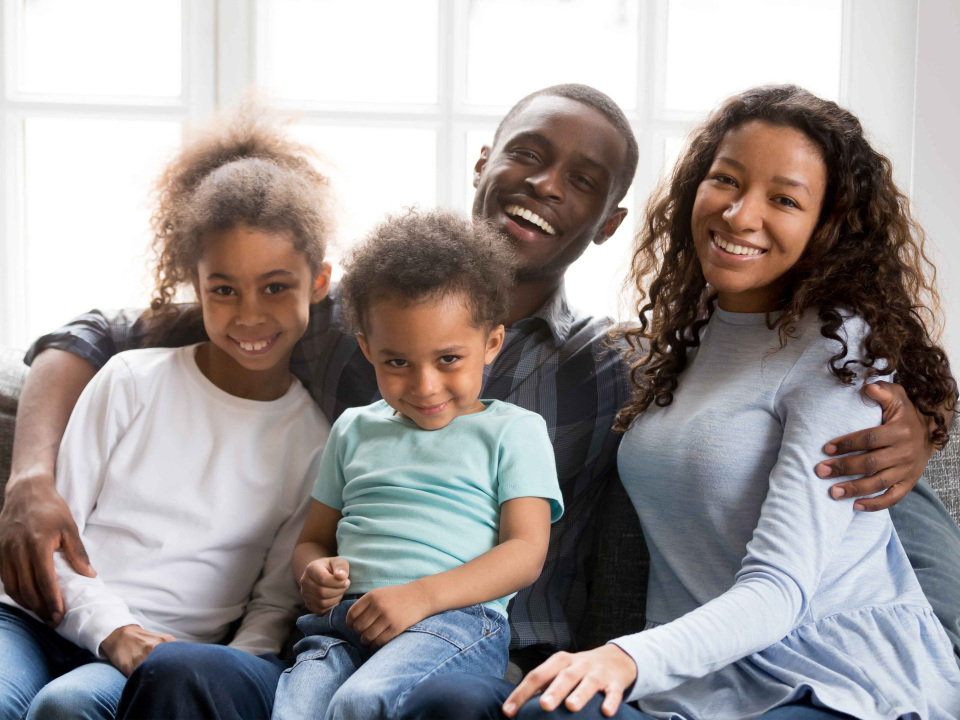 Family sitting in the living room smiling at the camera.
